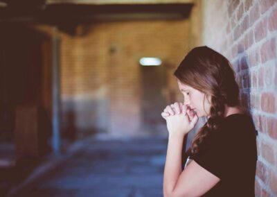 Lady Praying next to brick wall