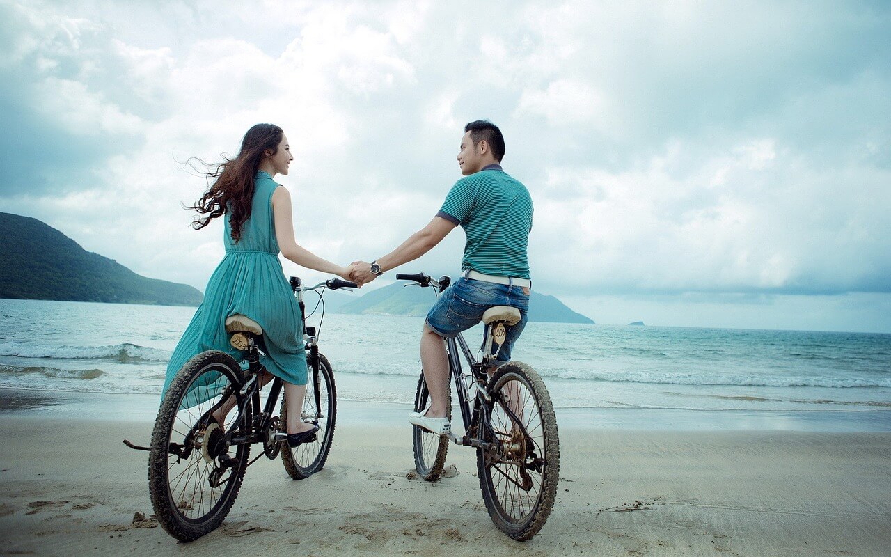 couple riding bikes by the beach
