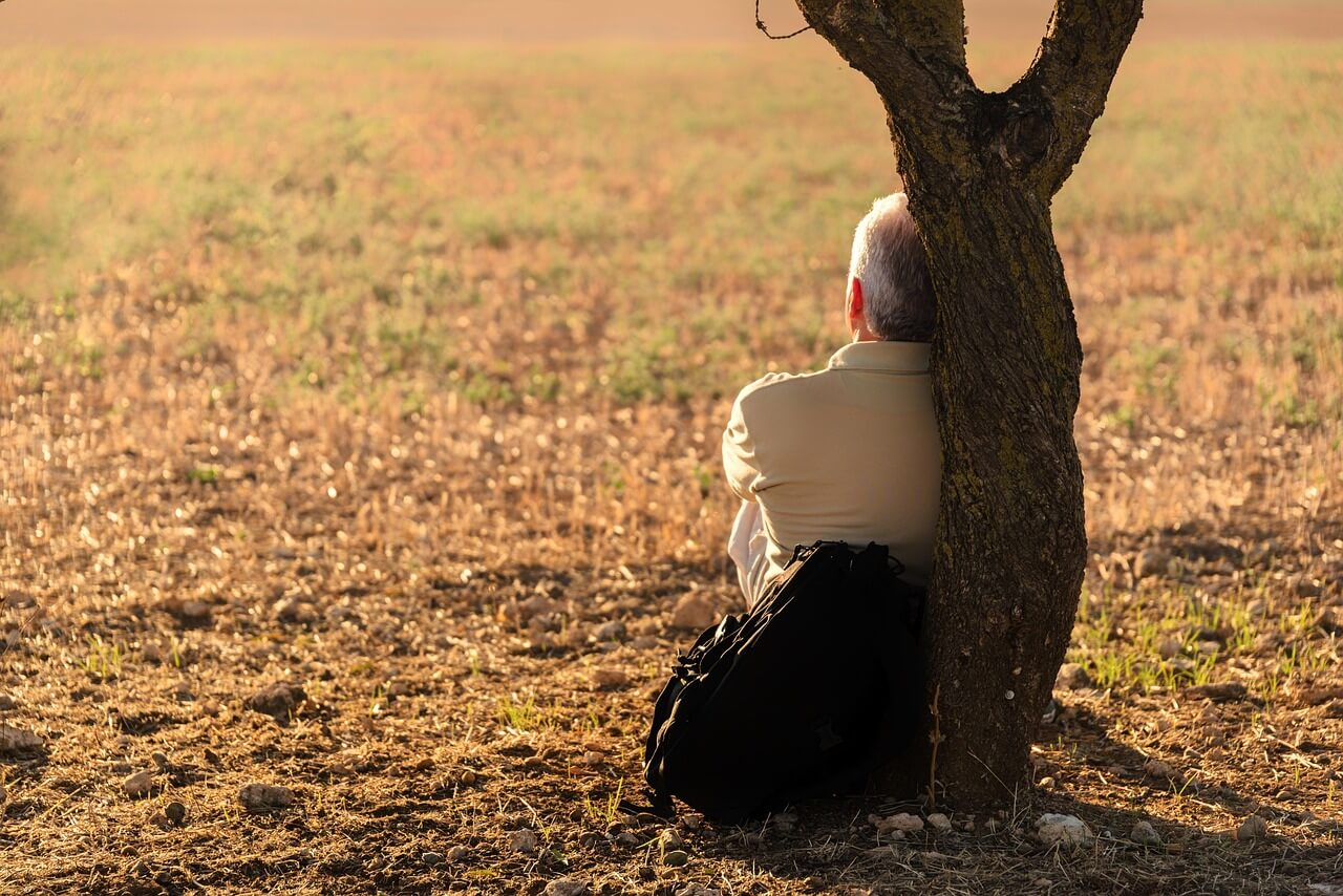 man contemplating next to a tree