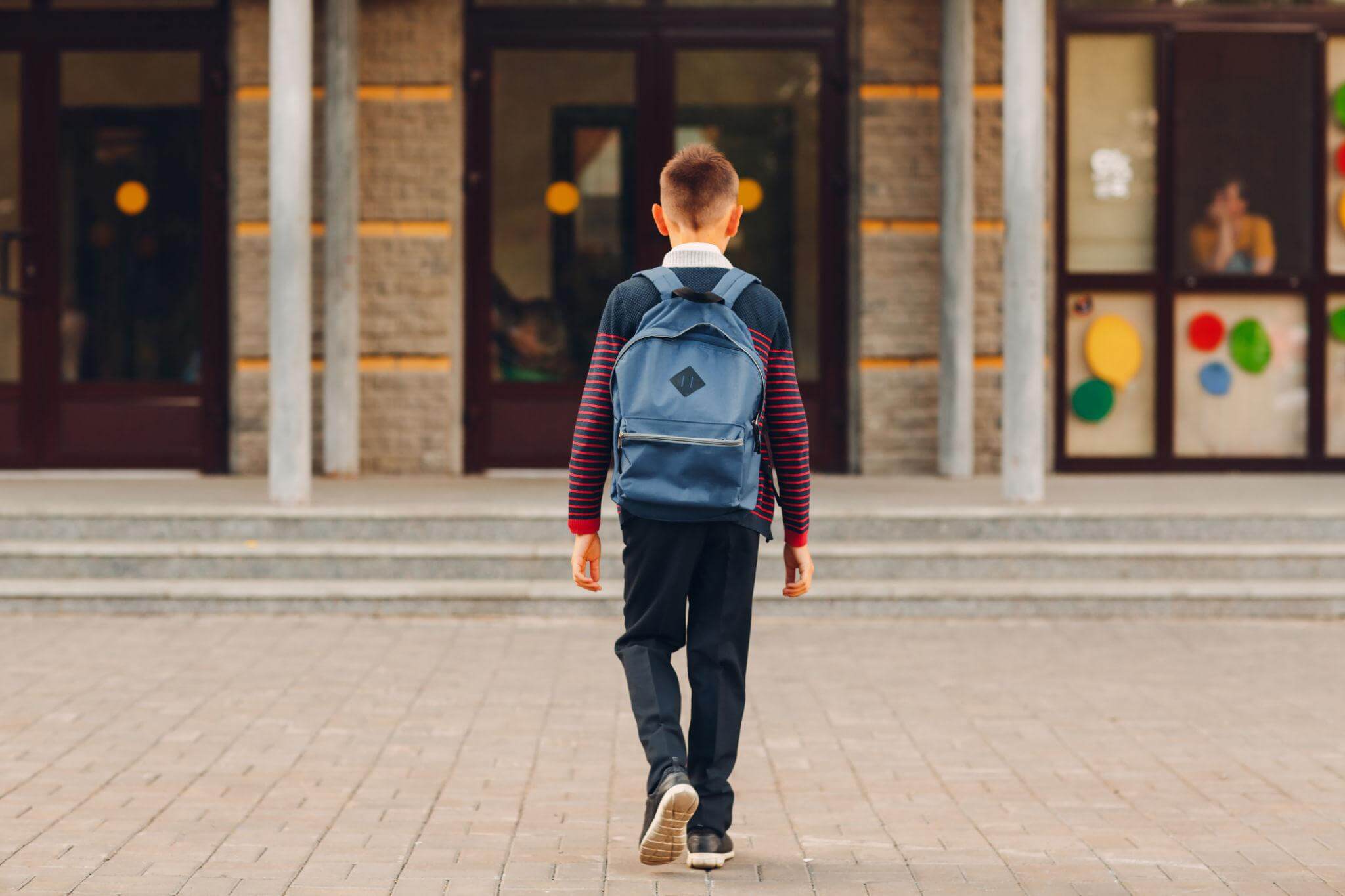 Student walking toward school with a backpack on the first days of a new school year